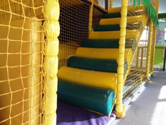 worn green and yellow entrance logs on soft play area