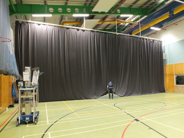 Repaired black sports arena curtain fitted